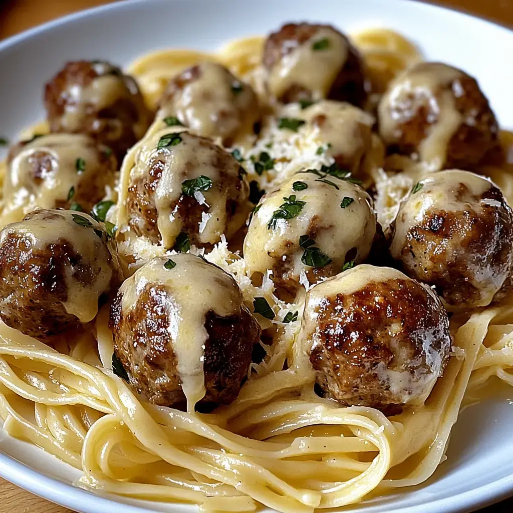 A bowl of spaghetti topped with cheese-covered meatballs and garnished with parsley.