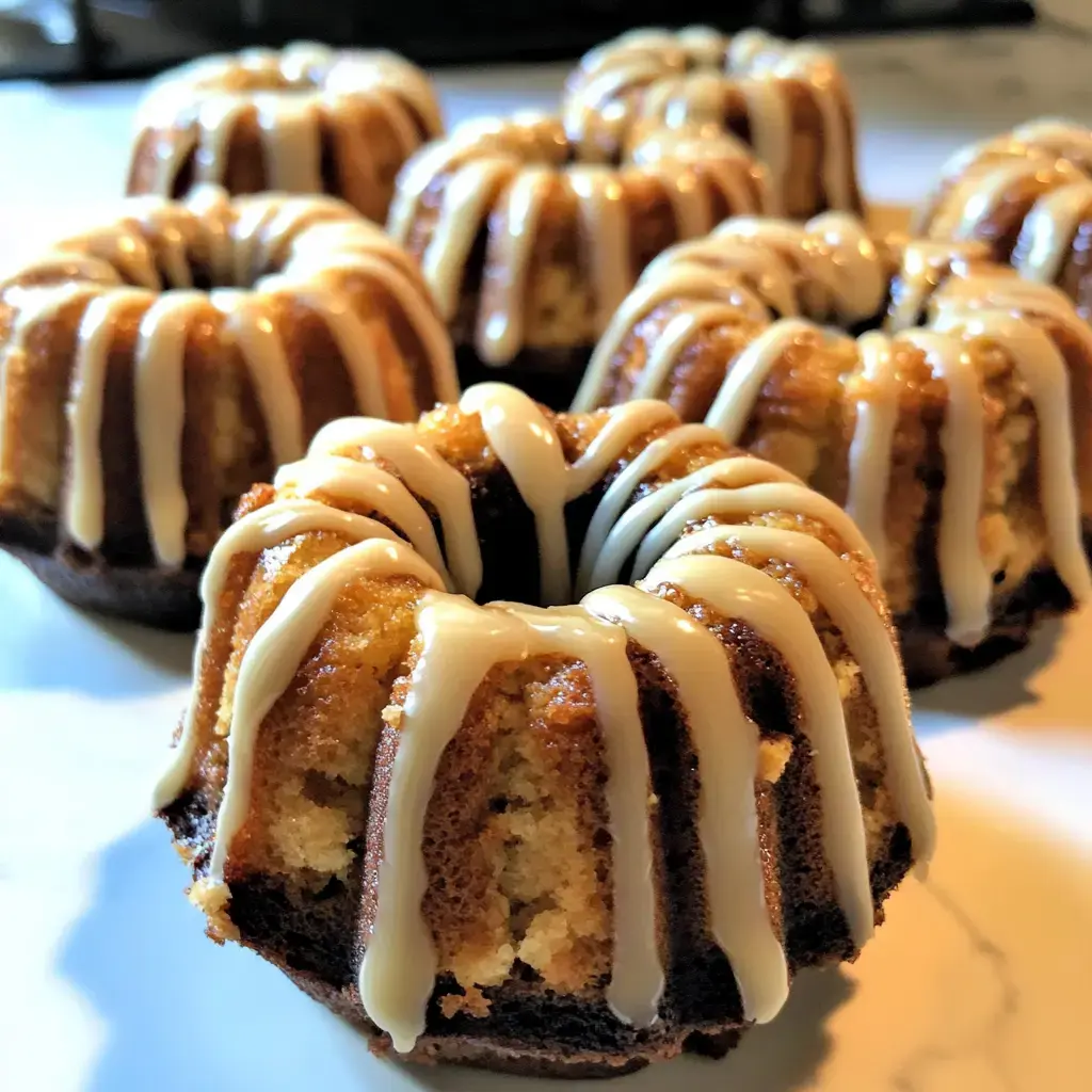 A close-up of several small bundt cakes drizzled with a light glaze.