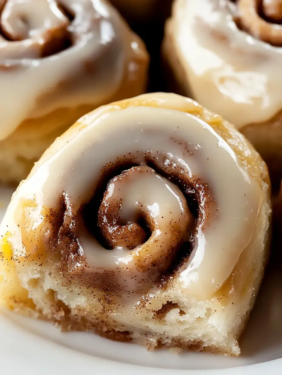 A close-up of a frosted cinnamon roll with a swirl of cinnamon and sugar.