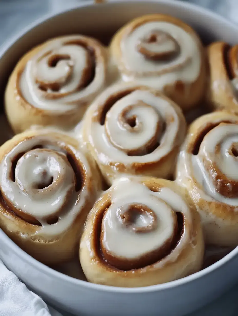 A round dish filled with freshly baked cinnamon rolls topped with creamy icing.