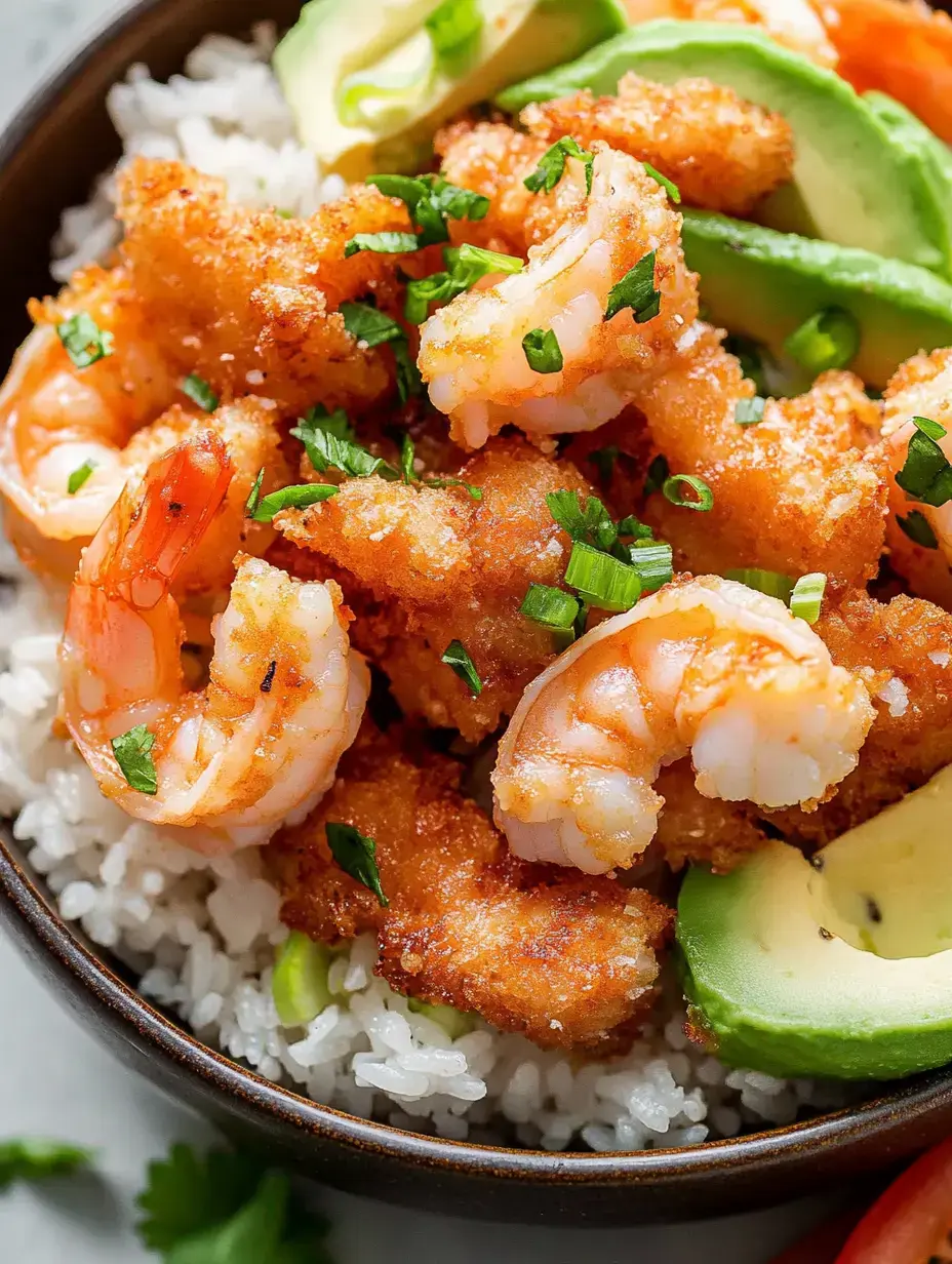 A bowl of white rice topped with crispy fried shrimp, garnished with chopped green onions and slices of avocado.