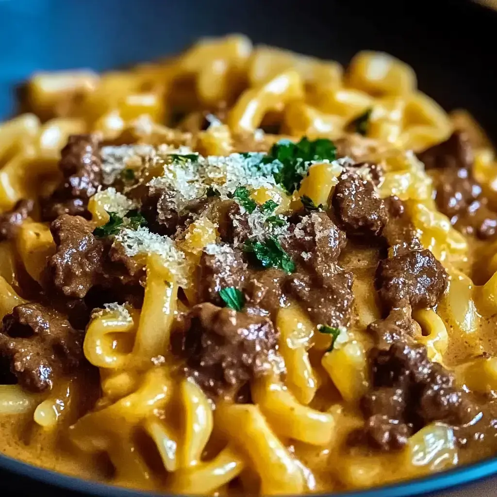 A close-up of pasta covered in a rich brown sauce, topped with grated cheese and fresh herbs.