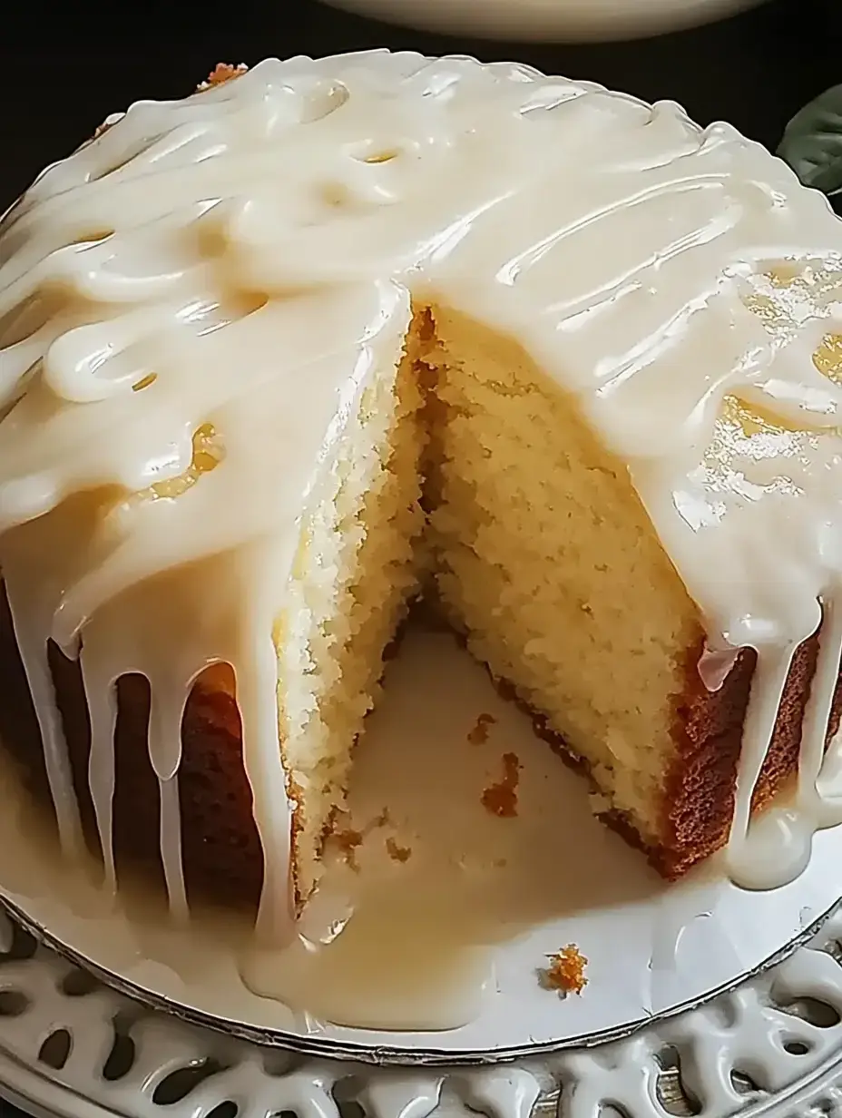 A freshly baked cake with a creamy glaze, partially sliced to reveal its soft interior.