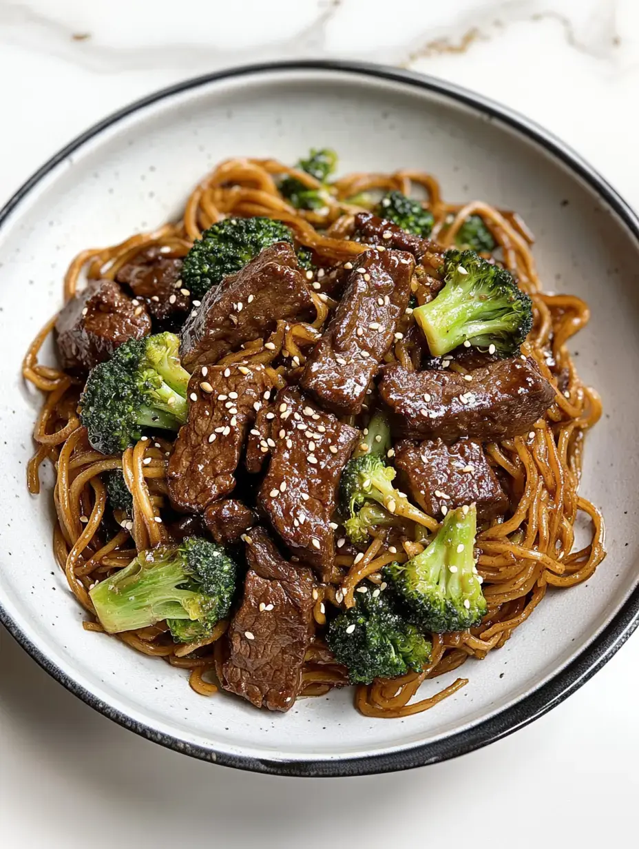 A bowl of stir-fried noodles with broccoli and pieces of beef, garnished with sesame seeds.