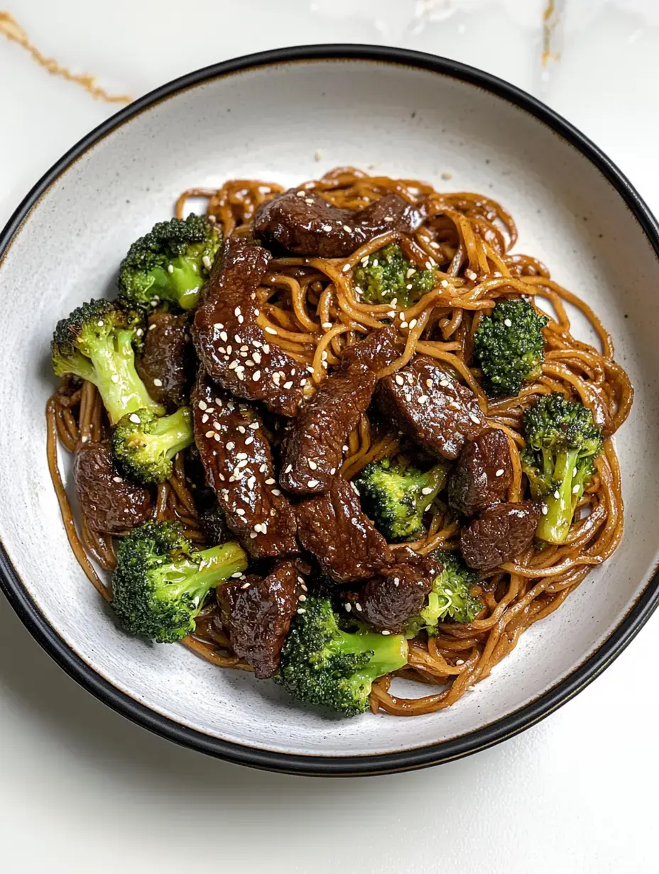 A bowl of noodles topped with pieces of beef and broccoli, garnished with sesame seeds.