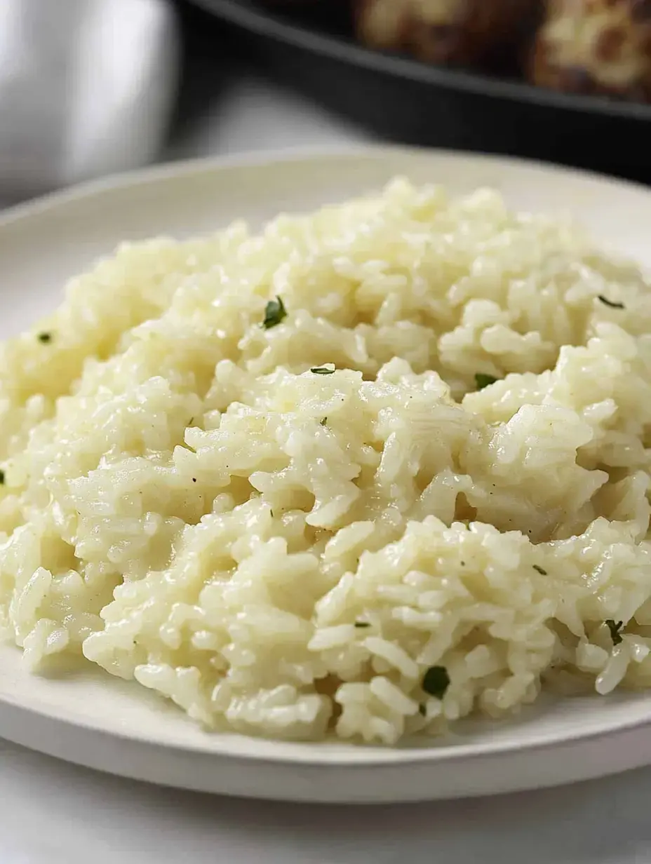 A plate of creamy, buttery rice with a sprinkle of herbs.