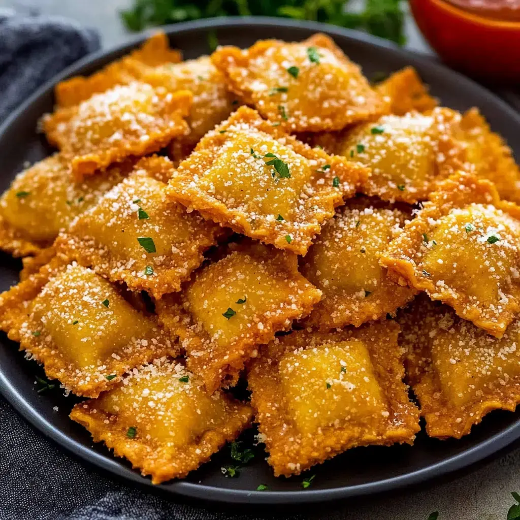 A black plate is filled with golden-brown, fried ravioli sprinkled with grated cheese and fresh parsley.