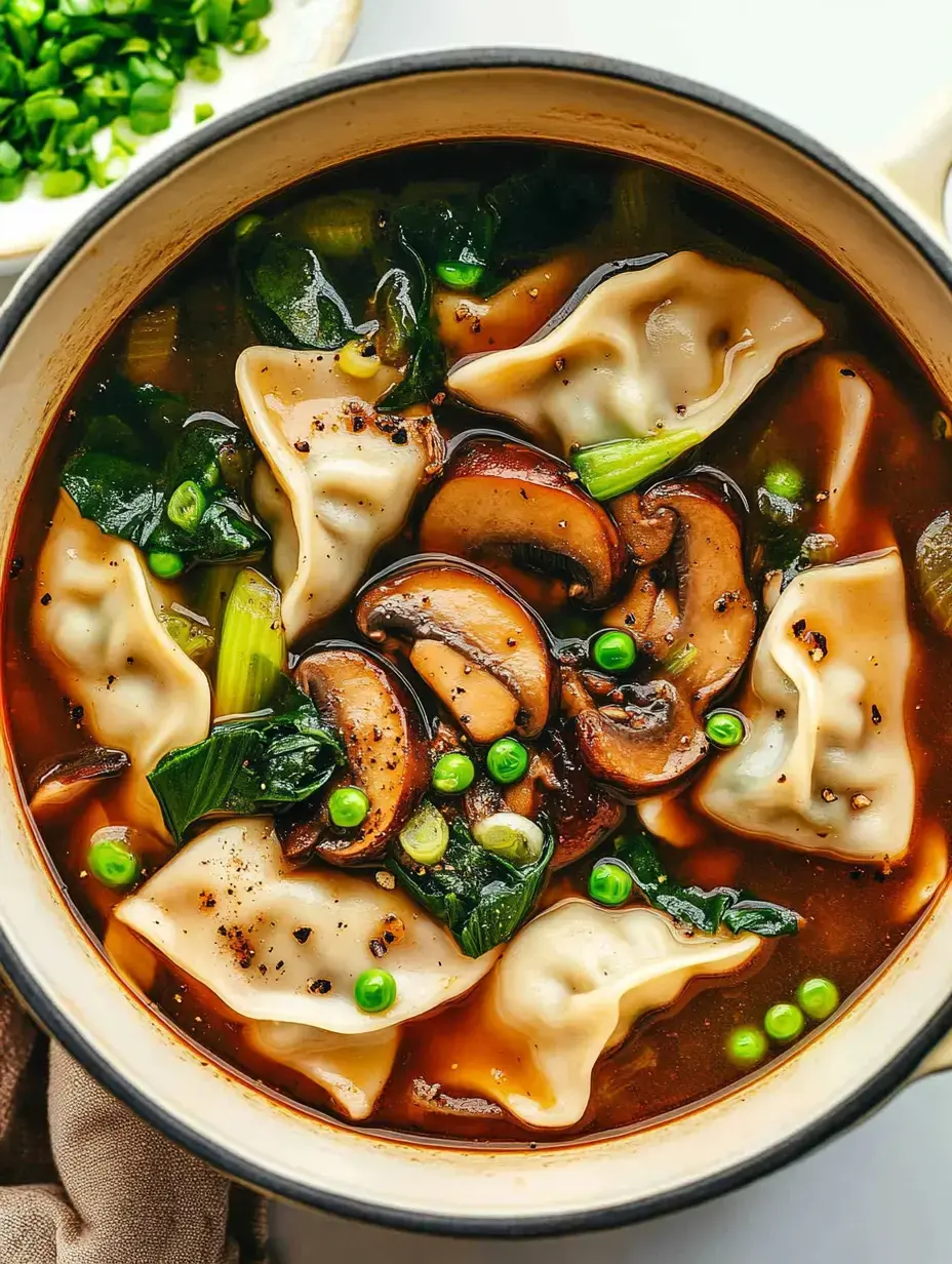 A close-up view of a bowl of dumpling soup with mushrooms, greens, and peas in a savory broth.