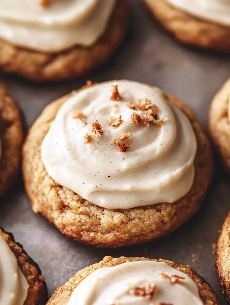 A close-up image of freshly baked cookies topped with creamy frosting and sprinkled with small crumbs.